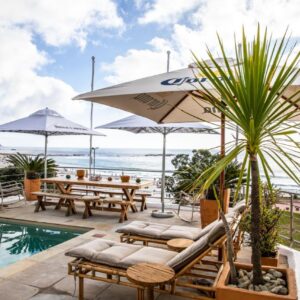 A patio with a table and chairs and a pool at Sea Castle Hotel Camps Bay in Cape Town