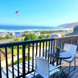 A balcony with a table and chairs and the ocean at Sea La Vie Beach House in Wilderness