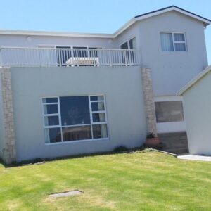 A white house with a lawn in front of it at Sea Spray Self Catering in Agulhas