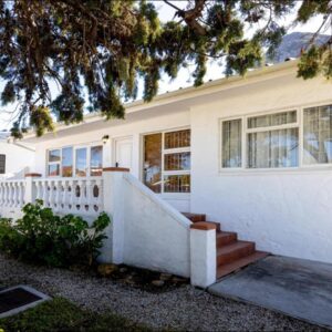 A white house with a staircase in front of it at SeaCrest Cottage in Hermanus