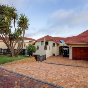 A house with a palm tree and a brick driveway at See the Sea Golf Estate Villa in Mossel Bay