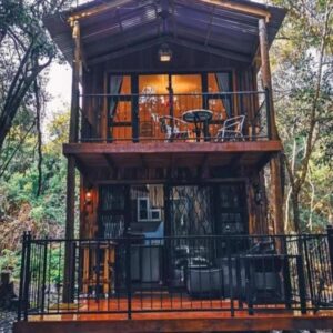 A tree house with a balcony in the woods at Shabby Fufu Lifestyle Farm in Plettenberg Bay