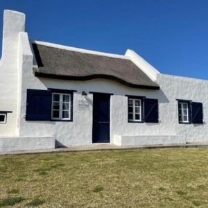 A white house with a black roof at Shoreline Cottage in Struisbaai