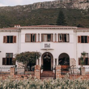 A white house with a mountain in the background at Sonnekus Boutique Hotel & Bistro in Kalk Bay