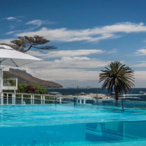 A swimming pool with an umbrella and the ocean at South Beach Camps Bay Boutique Hotel in Cape Town