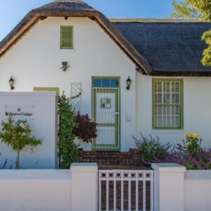 A white house with a white fence at Squirrel Cottage in Franschhoek