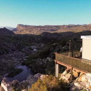 A house with a balcony overlooking a river at Stayatdestraadt Red Fin Cottage in Op-die-Berg