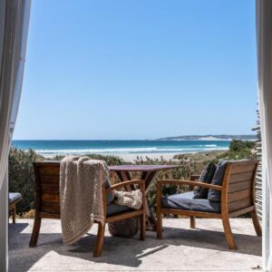 A patio with chairs and a view of the beach at Strandloper Ocean Boutique Hotel in Paternoster