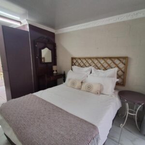 A bedroom with a bed with white sheets and pillows at Sufi'Sawd Guest Rooms Muizenberg in Muizenberg