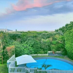 A swimming pool with a white fence and an umbrella at Swallows Nest Plett in Plettenberg Bay