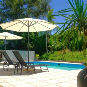 A patio with chairs and an umbrella and a pool at Swellendam Country Lodge - Guest House - B&B in Swellendam