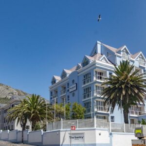 A large white building with a mountain in the background at The Bantry Aparthotel by Totalstay in Cape Town