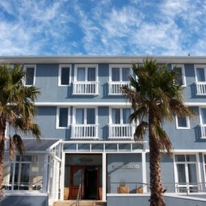 A blue building with palm trees in front of it at The Calders Hotel & Conference Centre in Fish hoek