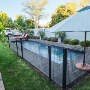 A fence with an umbrella next to a swimming pool at The Cottage Farm in Stellenbosch