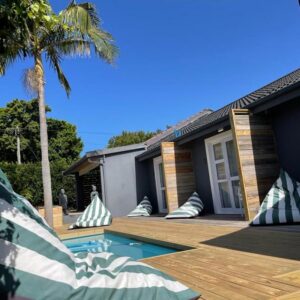 A house with a wooden deck and a swimming pool at The Door54 in Plettenberg Bay