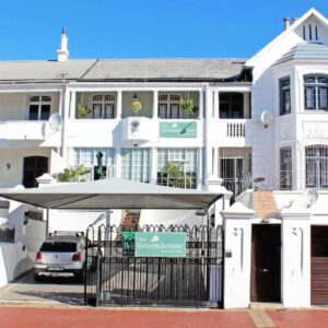 A white building with an umbrella in front of it at The Greenhouse Guesthouse in Cape Town