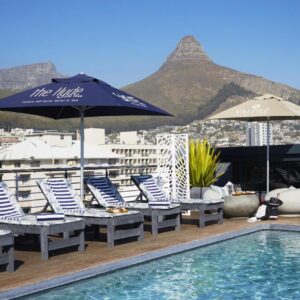 A pool with chairs and umbrellas on a rooftop at The Hyde All Suite Hotel in Cape Town
