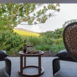 Two chairs and a table with a glass of wine on a patio at The Jordan Suites in Stellenbosch