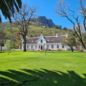 A large white house with a mountain in the background at The Manor at Mont Angelis Estate in Stellenbosch