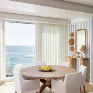 A dining room with a table and chairs with a view of the ocean at The Nici Clifton Sea View Apartments in Cape Town