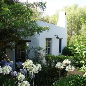 A white house with flowers in the yard at The Oil Mill Guesthouse in Swellendam