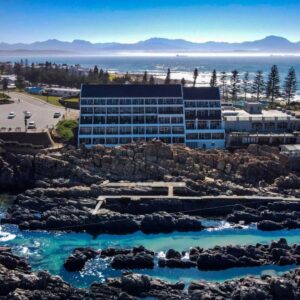 A building on the beach with rocks and water at The Point Hotel & Spa in Mossel Bay