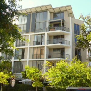 A tall white building with trees in front of it at The Quadrant Apartments in Cape Town