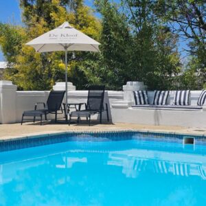 A swimming pool with a table and chairs and an umbrella at The Retreat Swellendam in Swellendam