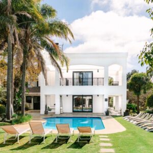 A house with a swimming pool and palm trees at The Salene Hotel & Apartments in Stellenbosch