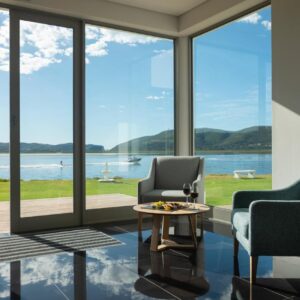 Two chairs and a table in front of a large window at St. James of Knysna in Knysna