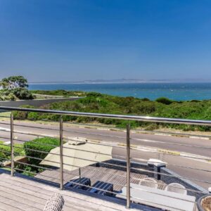 A balcony with a view of a road and the ocean at The Whale's Tale Guesthouse in Hermanus