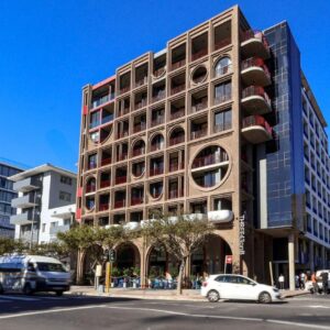 A tall building on a city street with cars at THREE43 ON B - Fluent Serviced Apartments in Cape Town