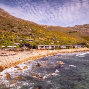 A beach with a rocky shore with a mountain at Tintswalo Atlantic in Hout Bay