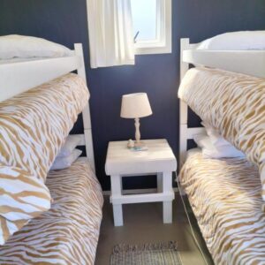 A bedroom with two bunk beds and a table with a lamp at Townsend Backpackers in Lambertʼs Bay