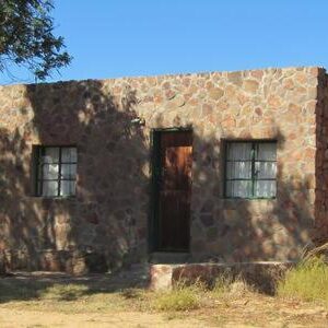A stone cottage with a wooden door and two windows at Traveller's Rest in the Cederberg
