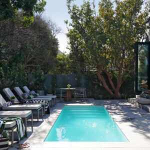 A backyard with a pool with chairs and a table at Twice Central Guest House in Stellenbosch