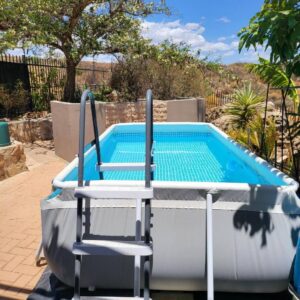 A pool with two chairs and a table and a swimming pool at Unpretentious peaceful Cottage in Clanwilliam