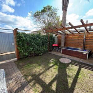 A backyard with a wooden pergola and a grill at Urban Nest Self Catering in George