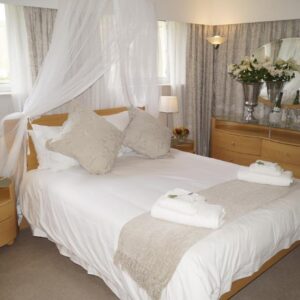 A bedroom with a white bed with a mirror at Valentines Hermanus in Hermanus