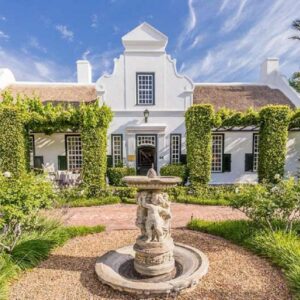 A large white house with a fountain in front of it at Van der Stel Manor in Stellenbosch