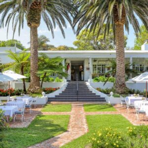 A view of the front of the resort with tables and palm trees at Villa Coloniale Schumacher Luxury Retreat, Adults Only in Cape Town