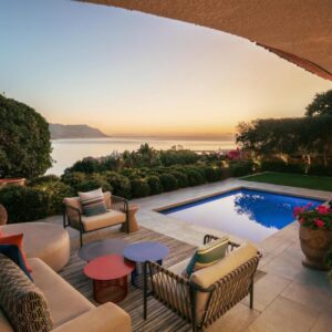 An outdoor patio with a pool and chairs and a table at Villa Coste Simon's Town in Simonʼs Town
