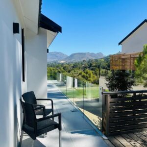 A pair of chairs on a porch with a fence at Vine and Valley Retreat in Cape Town