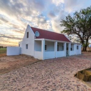A small white building with a red roof at Volmoed Cottage in Oudtshoorn