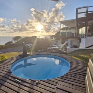 A swimming pool on a deck with the ocean in the background at Whales Way Ocean Retreat in Wilderness