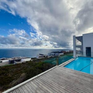 A house with a swimming pool next to the ocean at Whispering Waves - Pinnacle Point Estate in Mossel Bay