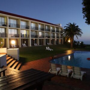 A hotel with a swimming pool in front of a building at Wilderness Beach Hotel in Wilderness