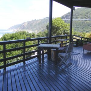 A wooden deck with a table and chairs on a house at Wilderness Beach House Backpackers Lodge in Wilderness