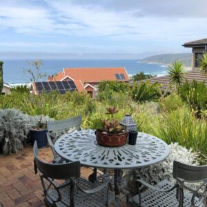 A patio with a table and chairs and the ocean at Wilderness Ocean View Cottage in Wilderness