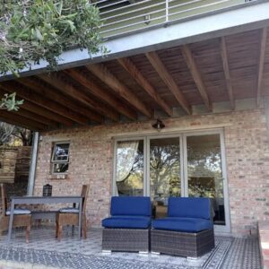 A patio with two blue chairs and a table at Wilderness Small Farm Stay in Wilderness
